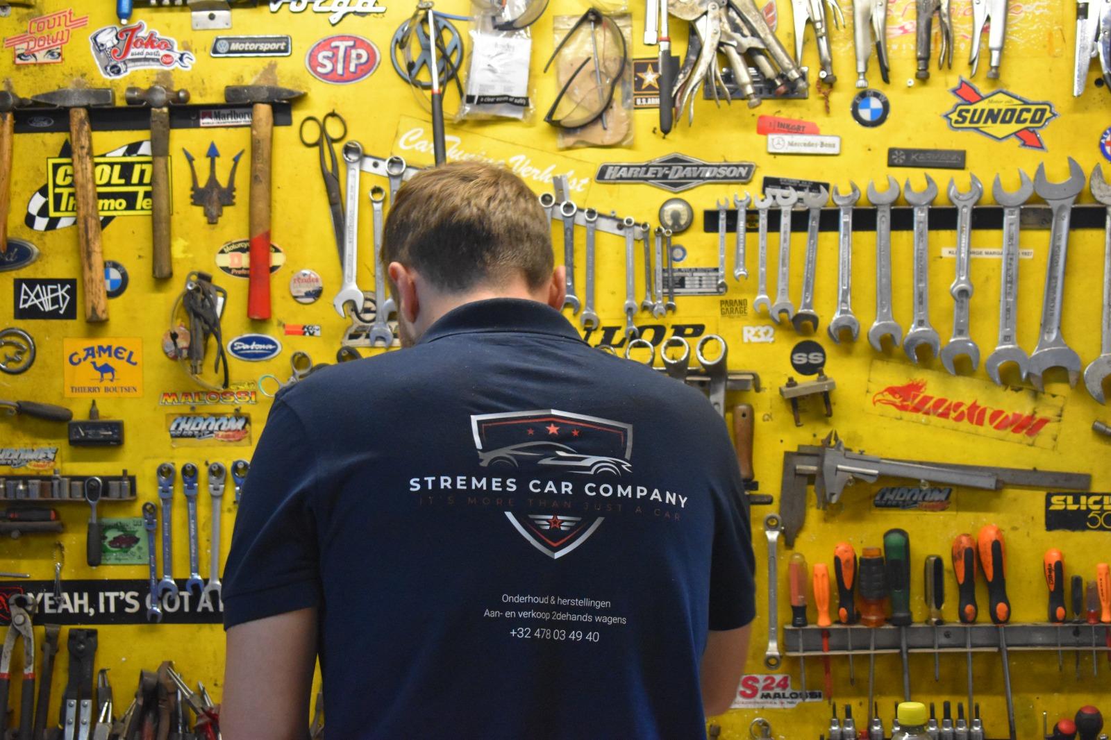 Medewerker in Stremes-polo voor de gereedschapswand van de werkplaats