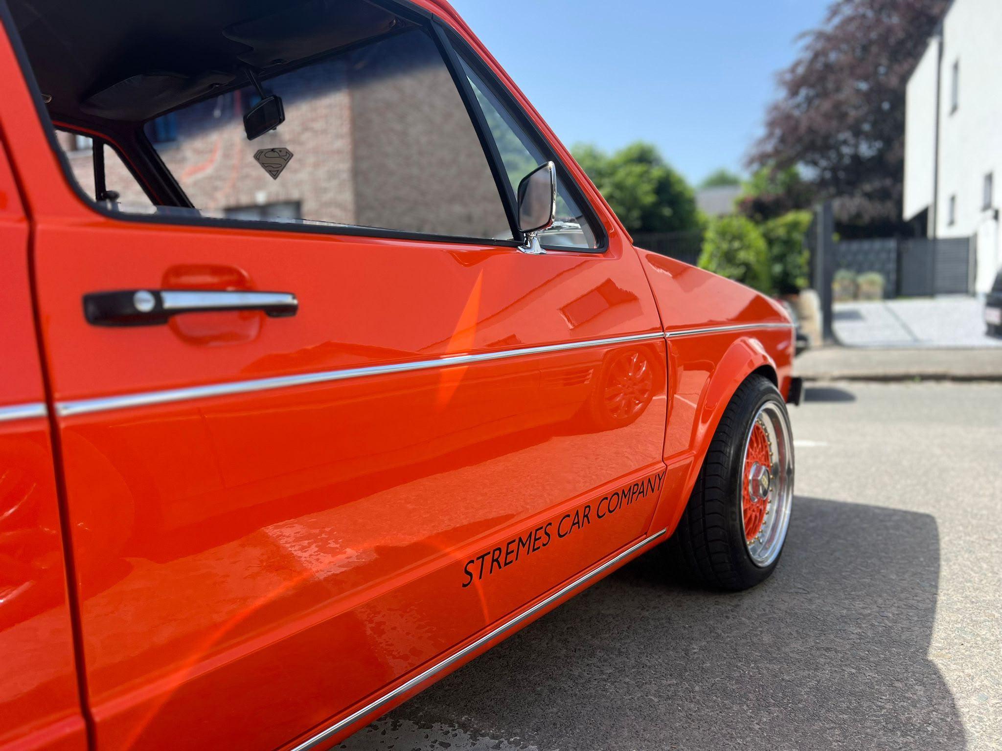 Detail van het lakwerk op een rode Golf met de belettering van Stremes Car Company
